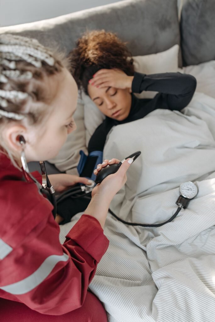 Paramedic measuring the blood pressure of a sick woman lying on a sofa