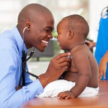 Smiling doctor listening to a baby's chest with a stethoscope